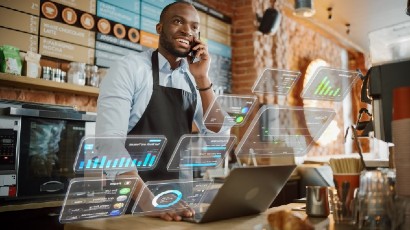 business checking near syracuse ny panel image of customer on phone with someone and looking at laptop with graphs