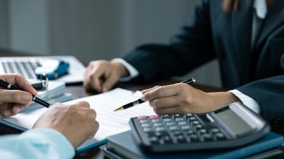 auto loans near syracuse ny panel image of client signing auto loan paperwork with a calculator and a pen at secny fcu