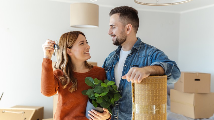 happy couple in home with keys and plant looking to refinance their mortgage with SECNY FCU near Syracuse NY