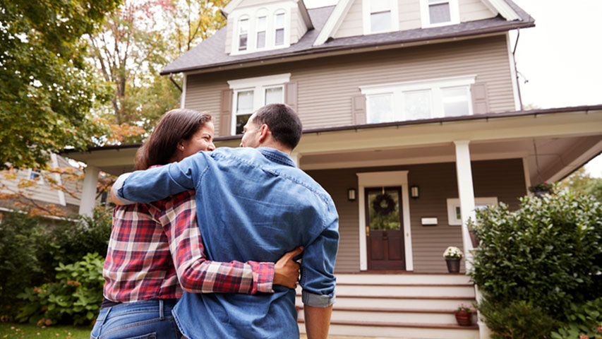 first time homebuyer programs near syracuse ny couple holding each other while smiling and walking towards new home