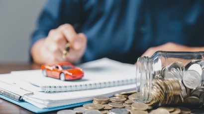 Auto Loan Rates & Personal Loan Rates near syracuse ny panel image for secny fcu client writing out auto plan with coins paper and a toy car